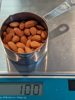 Image of a cup of on a scale almost full of almonds